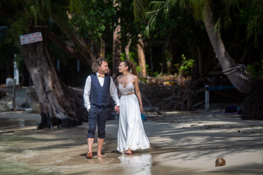 bride and groom walk on haad khom beach in koh phangan thailand