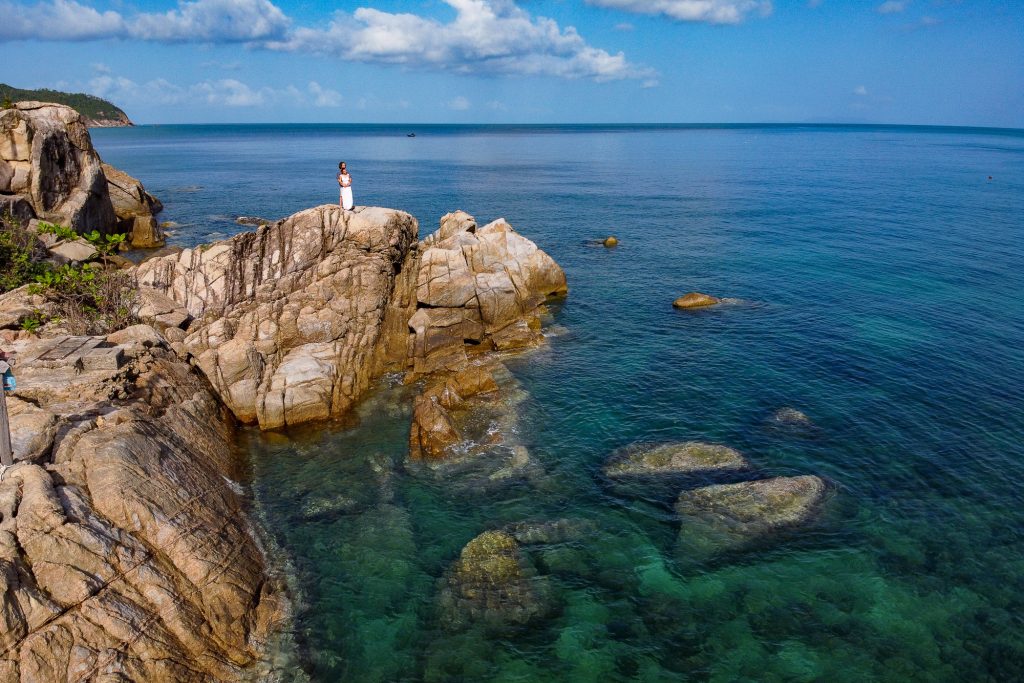 bride and groom walking on rocks in haad khom koh phangan thailand