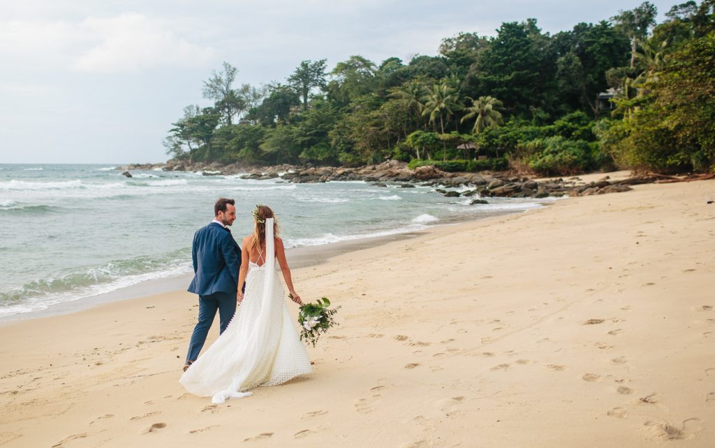bride and groom walk along the beach at Trisara resort Phuket Thailand for Style Me Pretty Magazine