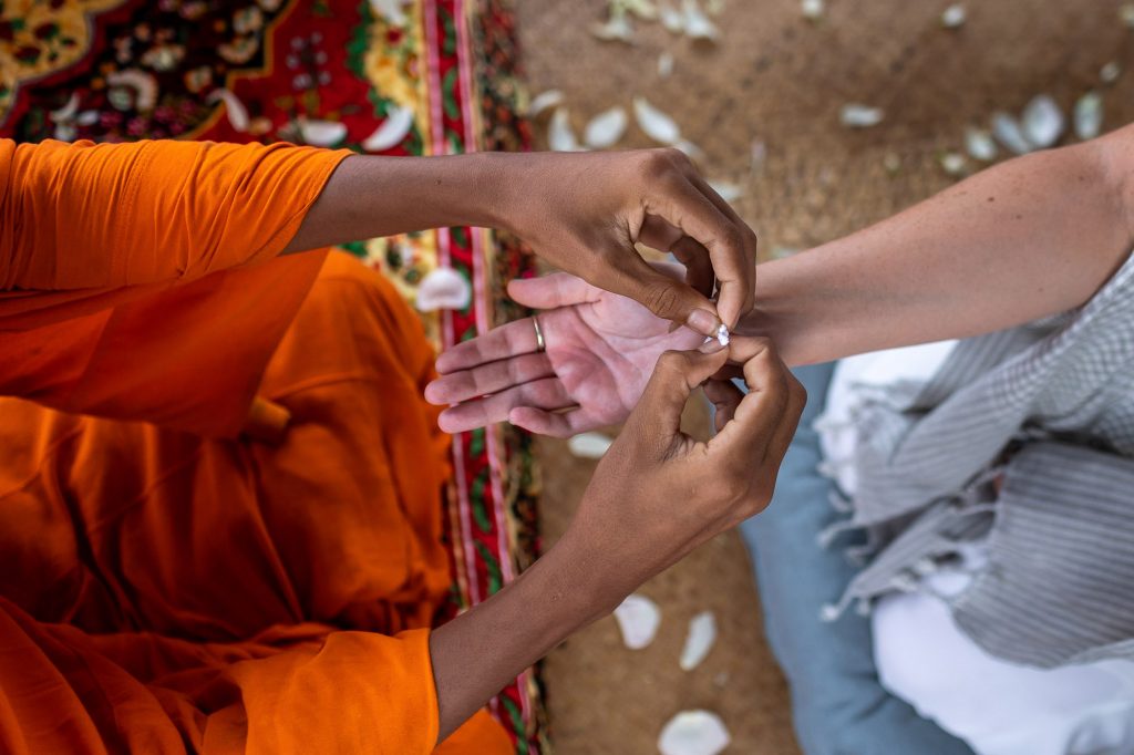 monk ties a bracelet around brides wrist at Song Saa Private Island in Cambodia
