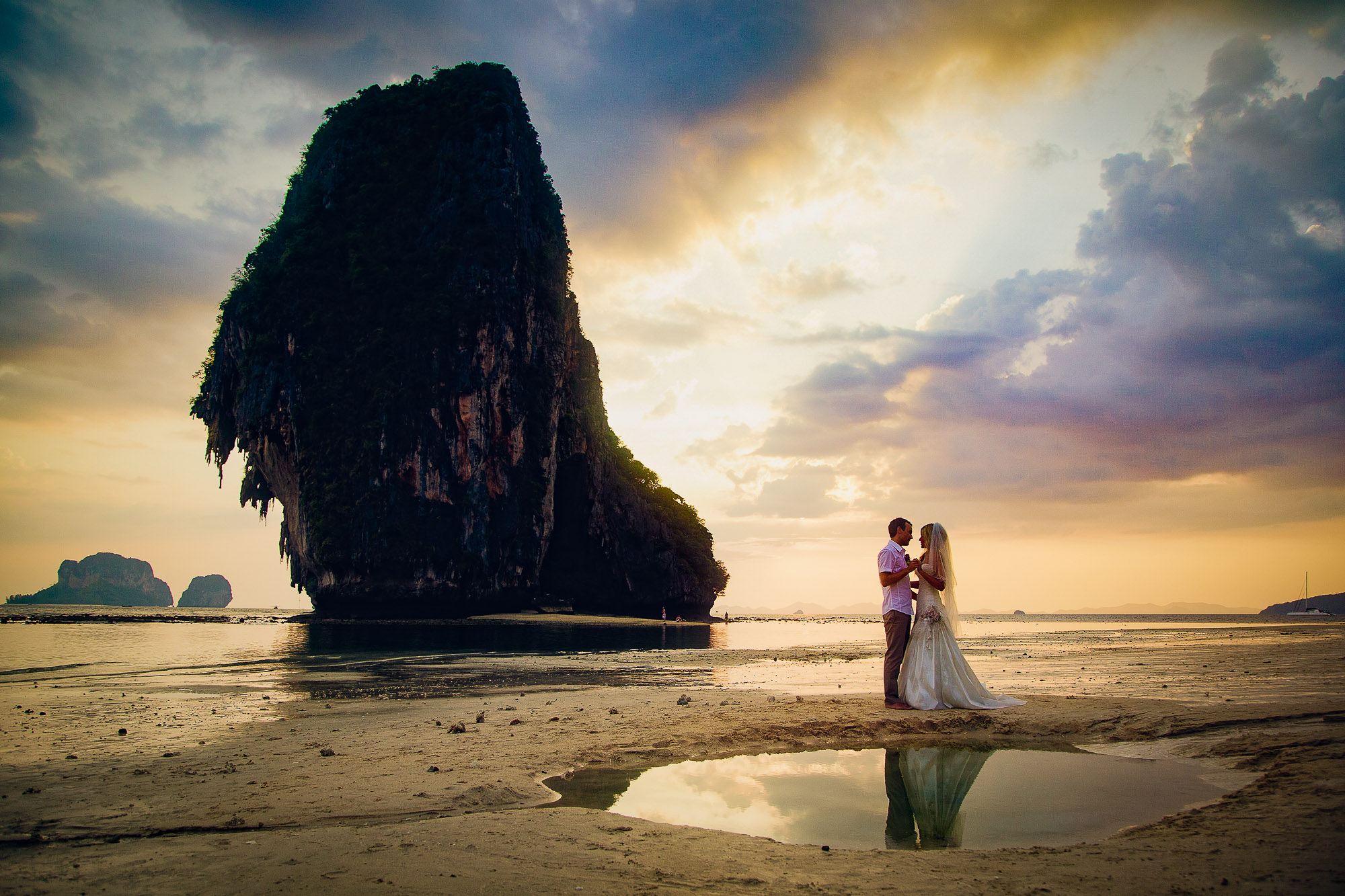 The bride and groom kiss on Phranang beach outside Rayavadee resort which is a top Thailand wedding venue
