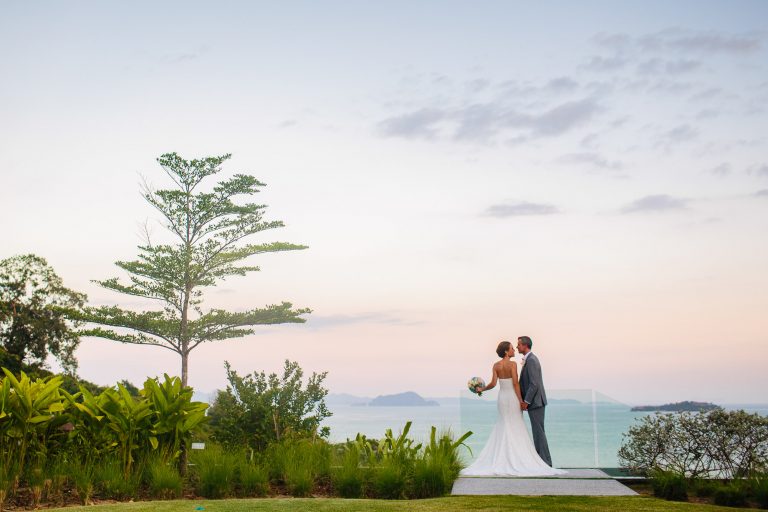 Bride and groom kiss in front of the ocean at their COMO Point Yamu Phuket Thailand Wedding